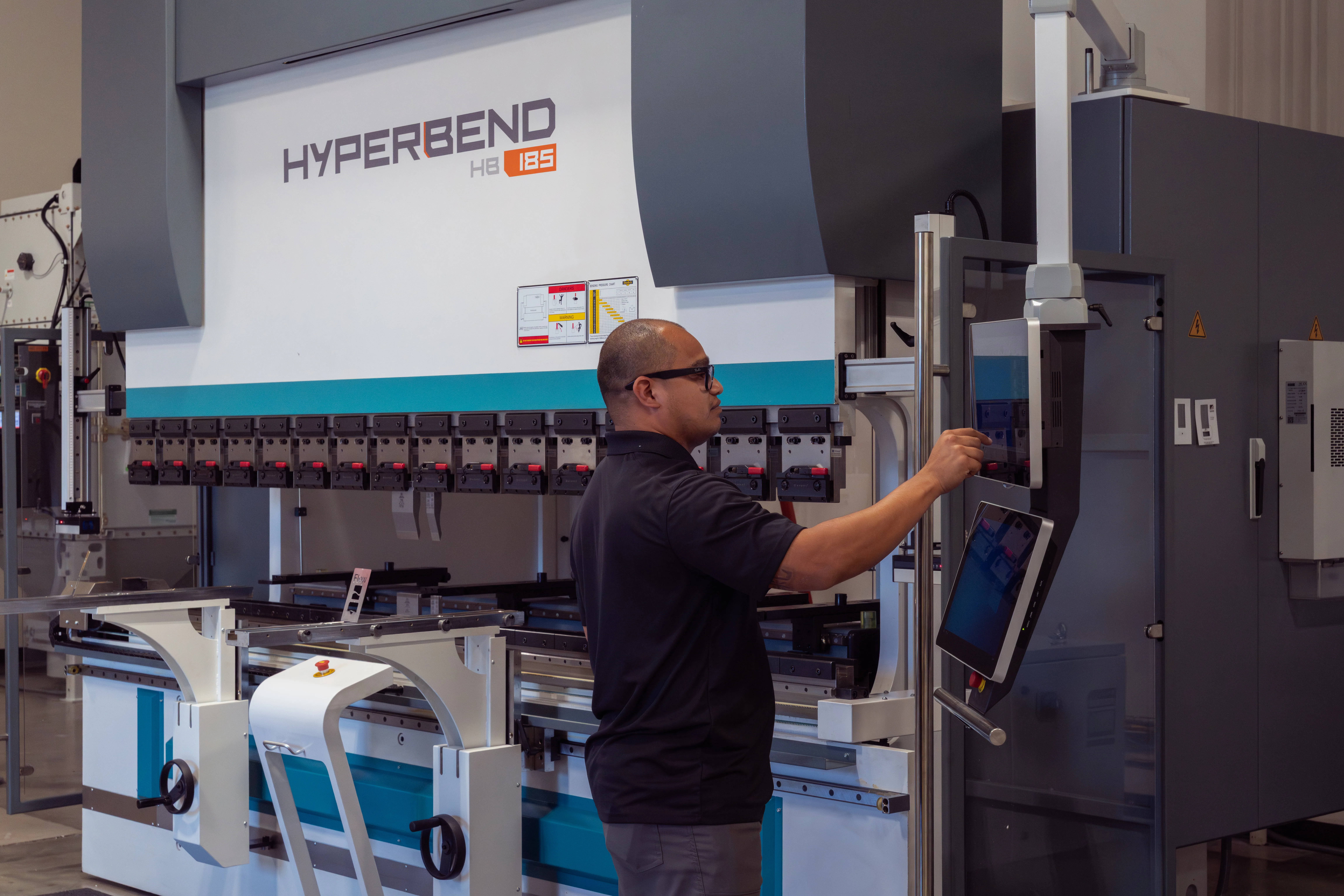 Technician performing maintenance on a HyperBend press brake, specifically using the touchscreen